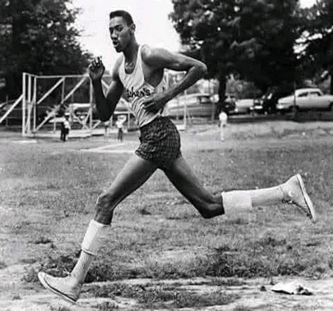 A black-and-white photo of a male track athlete in vintage running gear sprinting on grass, with overlaid text reading 'i'm…