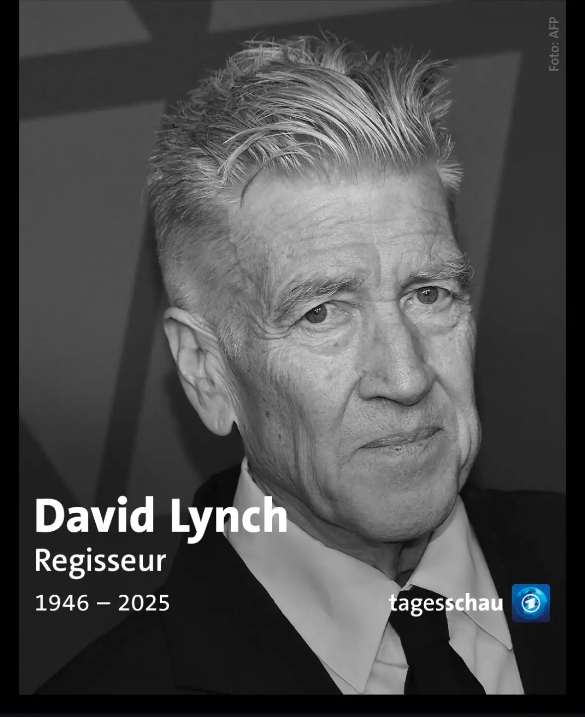 A black and white portrait of David Lynch, an older man with graying hair, wearing a suit and tie, looking off to the side…