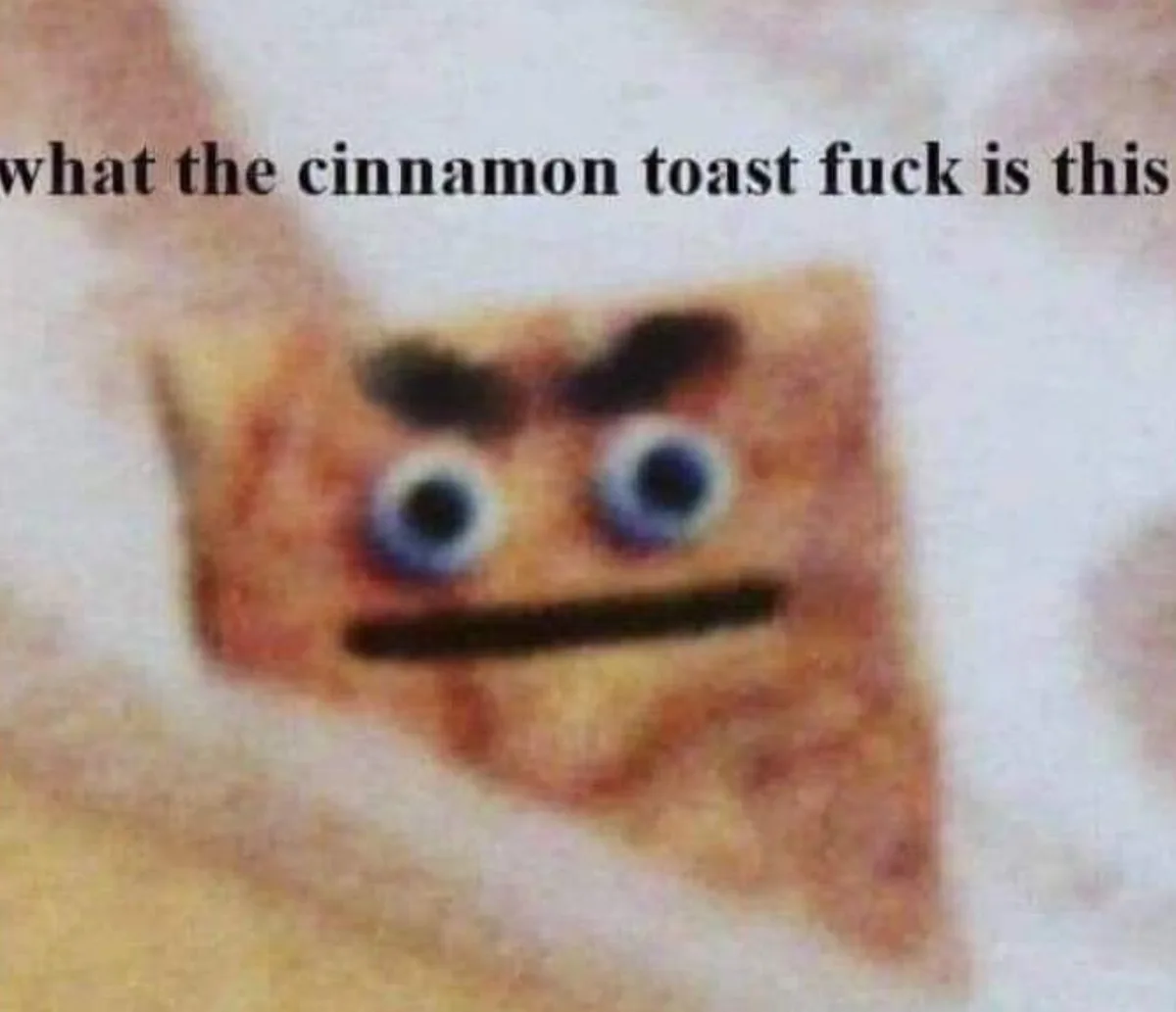 A blurry image of a square, brownish object resembling a piece of cinnamon toast with cartoonish blue eyes, dark eyebrows…
