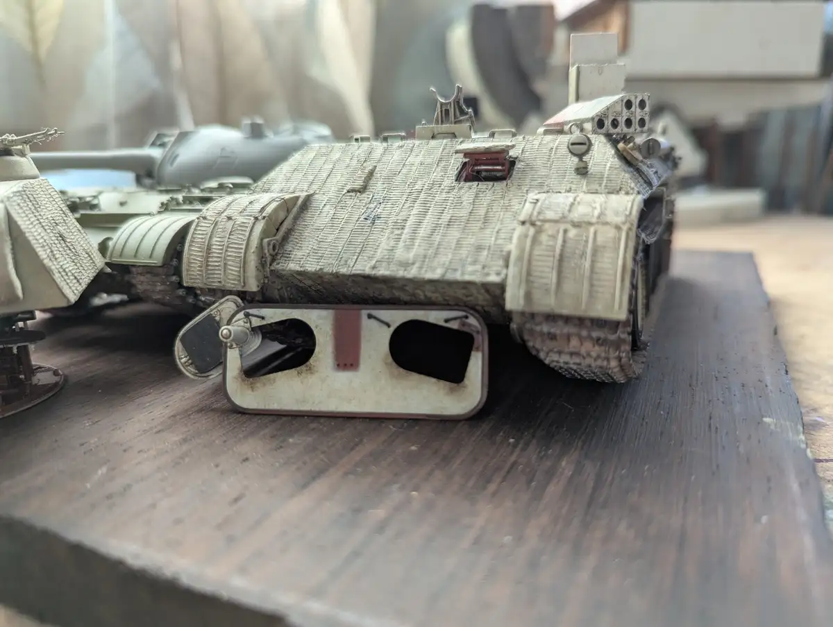 A detailed, weathered model of a futuristic armored vehicle, resembling a tank, sits on a wooden surface. The vehicle has a…