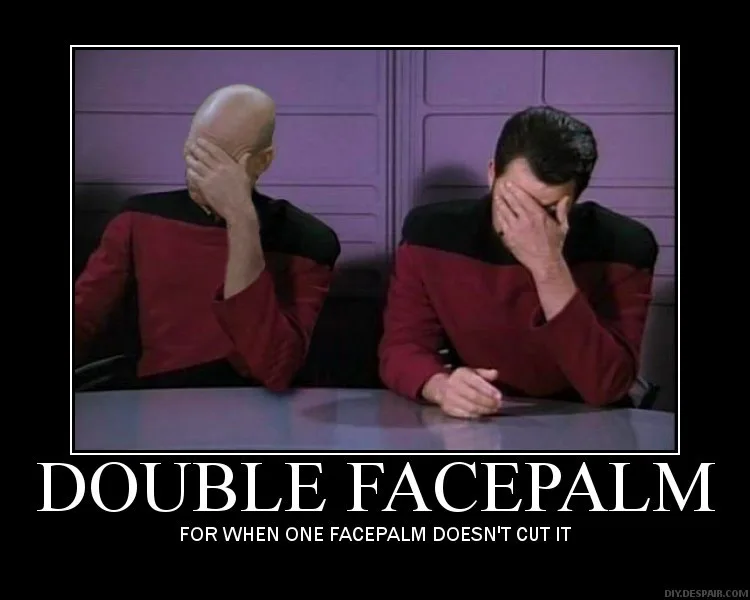 Two men in red and black Starfleet uniforms sit at a table, both covering their faces with their hands in a facepalm…