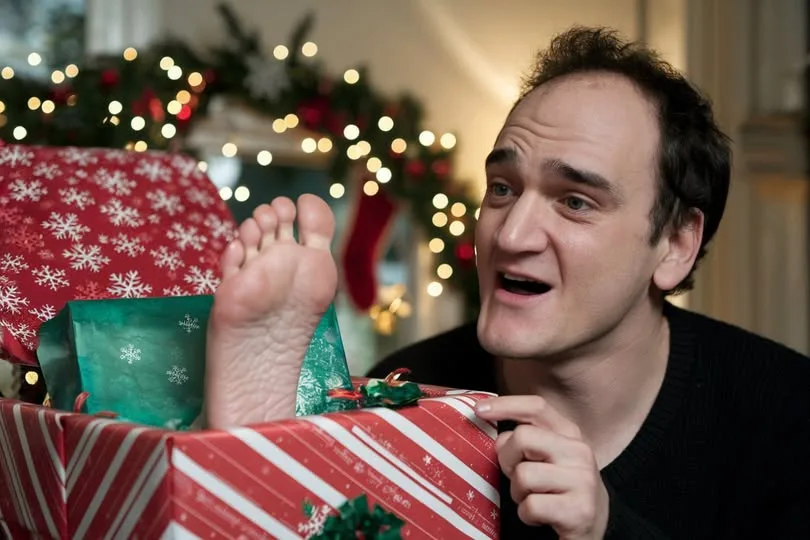 a man with a surprised expression looks at his bare foot sticking out of a red and white striped christmas present, with…
