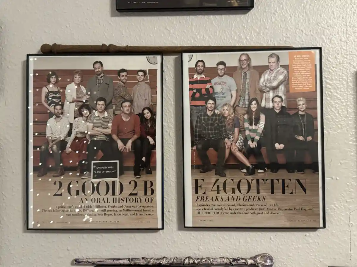 Two framed Vanity Fair magazine covers from January 2013 hang side-by-side on a wall, both featuring the cast of the TV show…