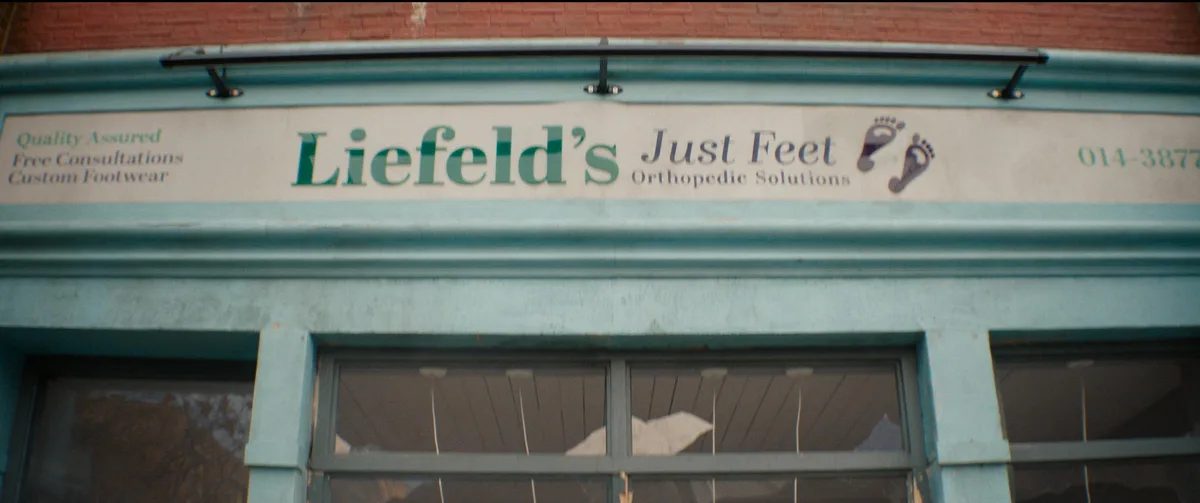 A storefront sign for 'Liefeld's Just Feet Orthopedic Solutions' with foot icons and contact info, humorously implying the…