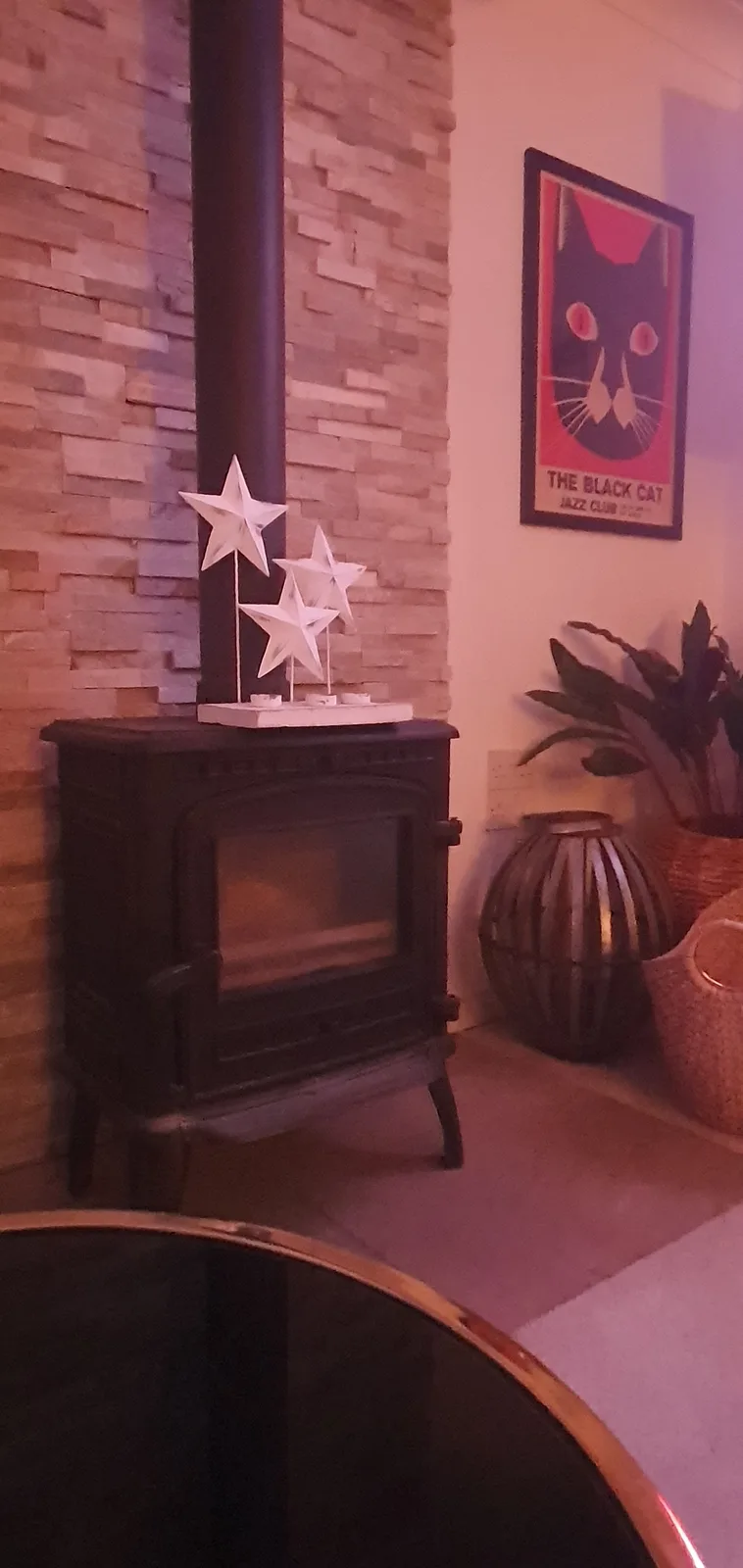 A cozy indoor scene featuring a black wood-burning stove with three white decorative stars on top, set against a stacked…