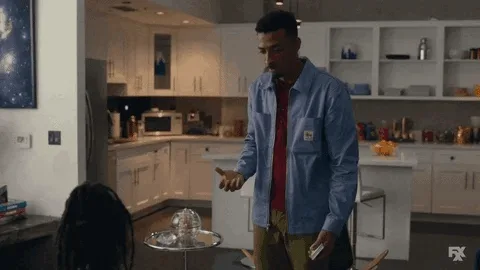 A man in a blue shirt and red undershirt stands in a modern kitchen, gesturing as he asks a question. The overlaid text…