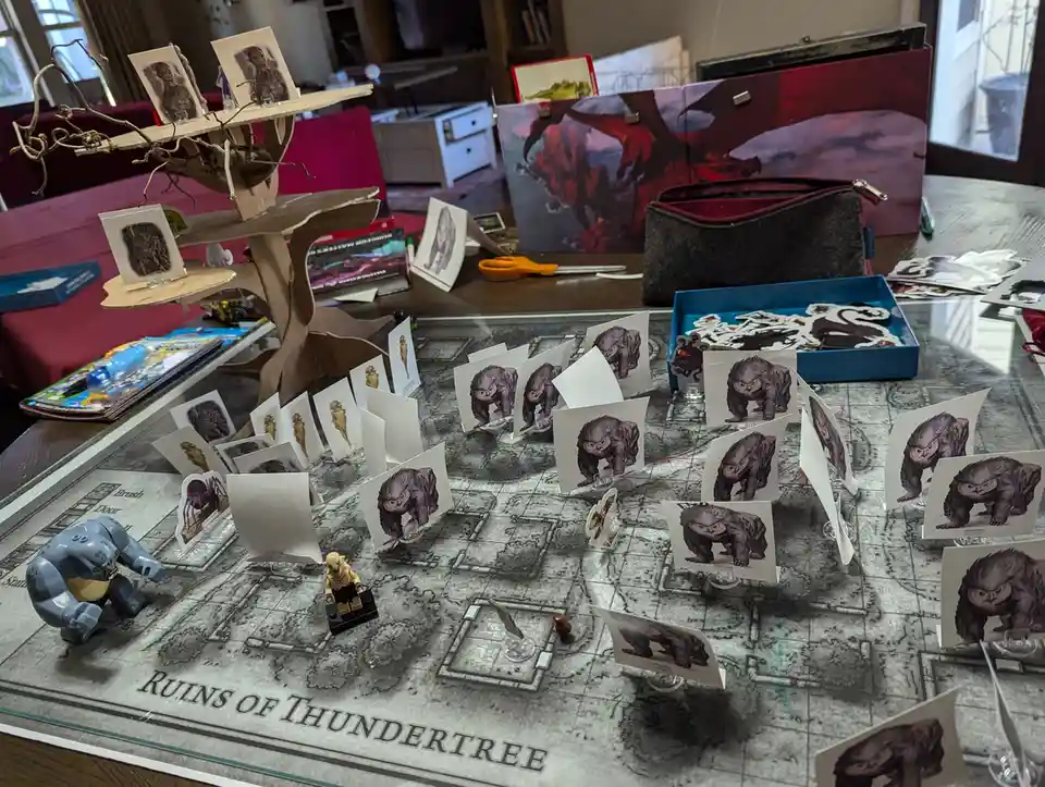 A tabletop role-playing game setup on a map titled 'Ruins of Thundertree' is cluttered with numerous identical cardboard…