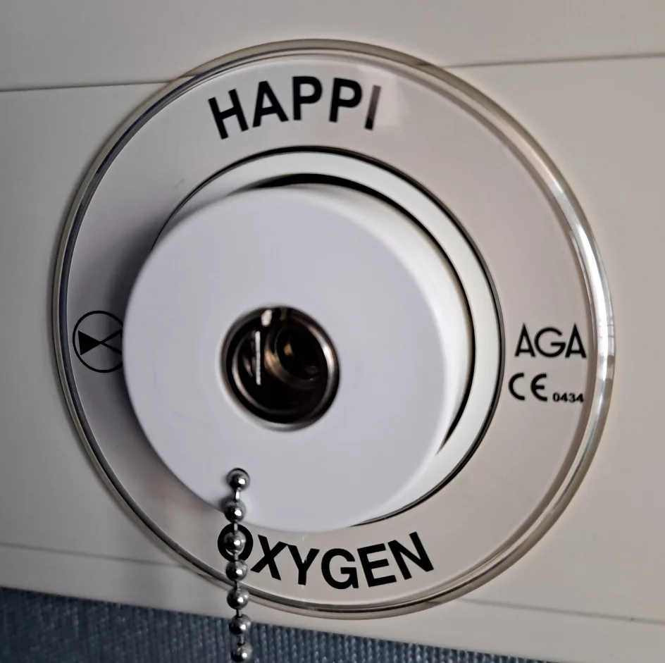 A close-up of a white circular appliance control knob with a metal ball chain pull. The word 'HAPPI' is printed at the top…
