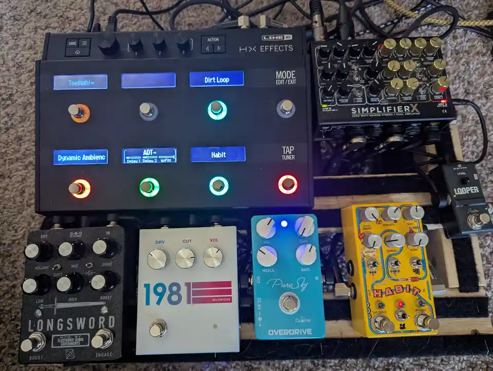 An overhead photo of a musician's pedalboard featuring a Line 6 HX Effects unit with multiple illuminated footswitches…