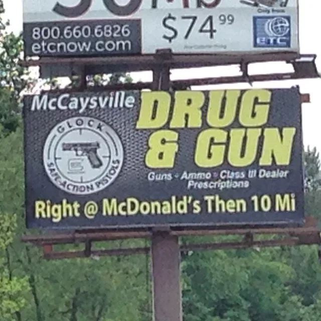 A billboard for a business in McCaysville advertising 'DRUG & GUN' with a Glock logo, listing 'Guns - Ammo - Class III…