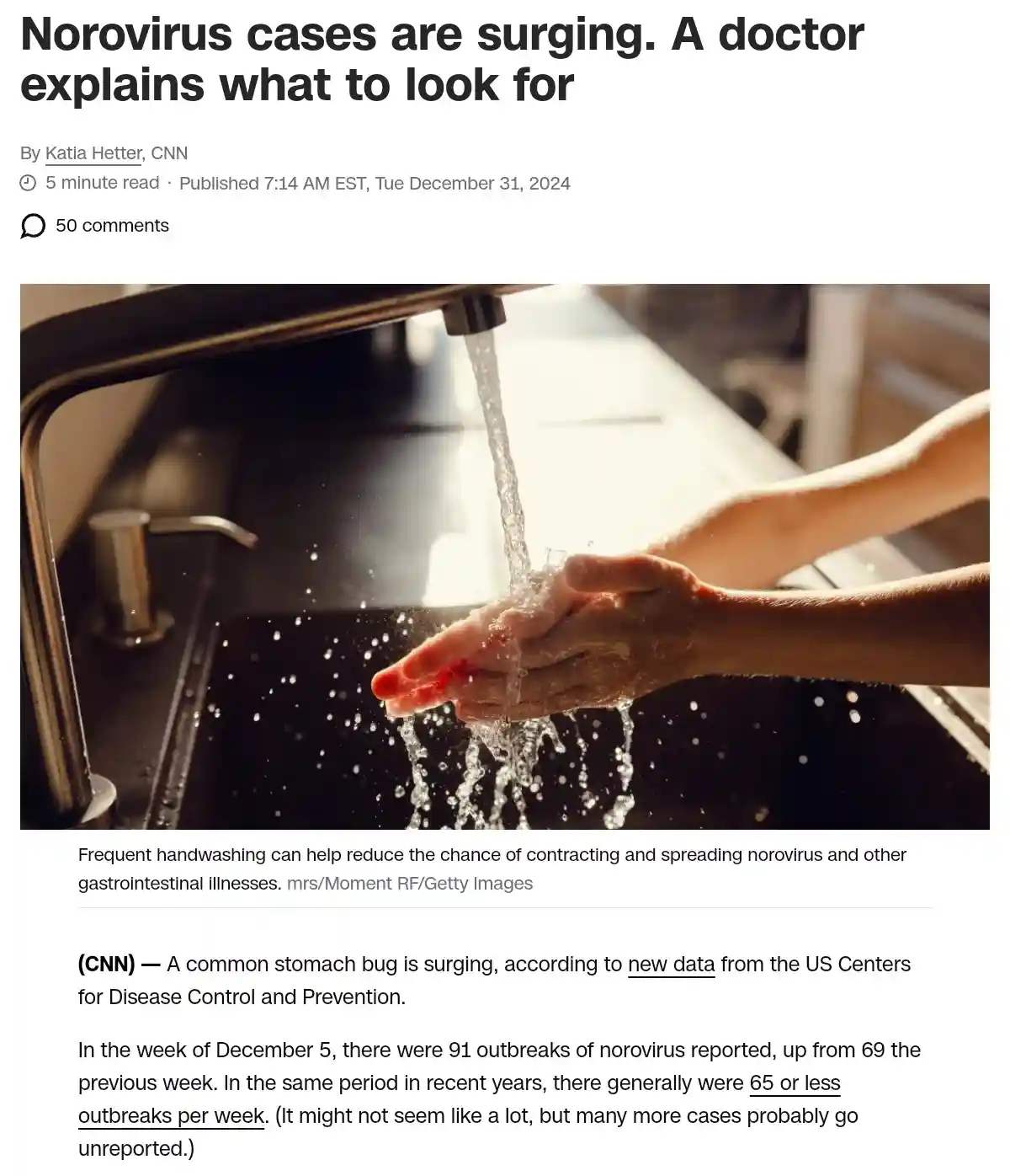 A close-up photo shows a person washing their hands under a running faucet in a kitchen sink, with water splashing. The…