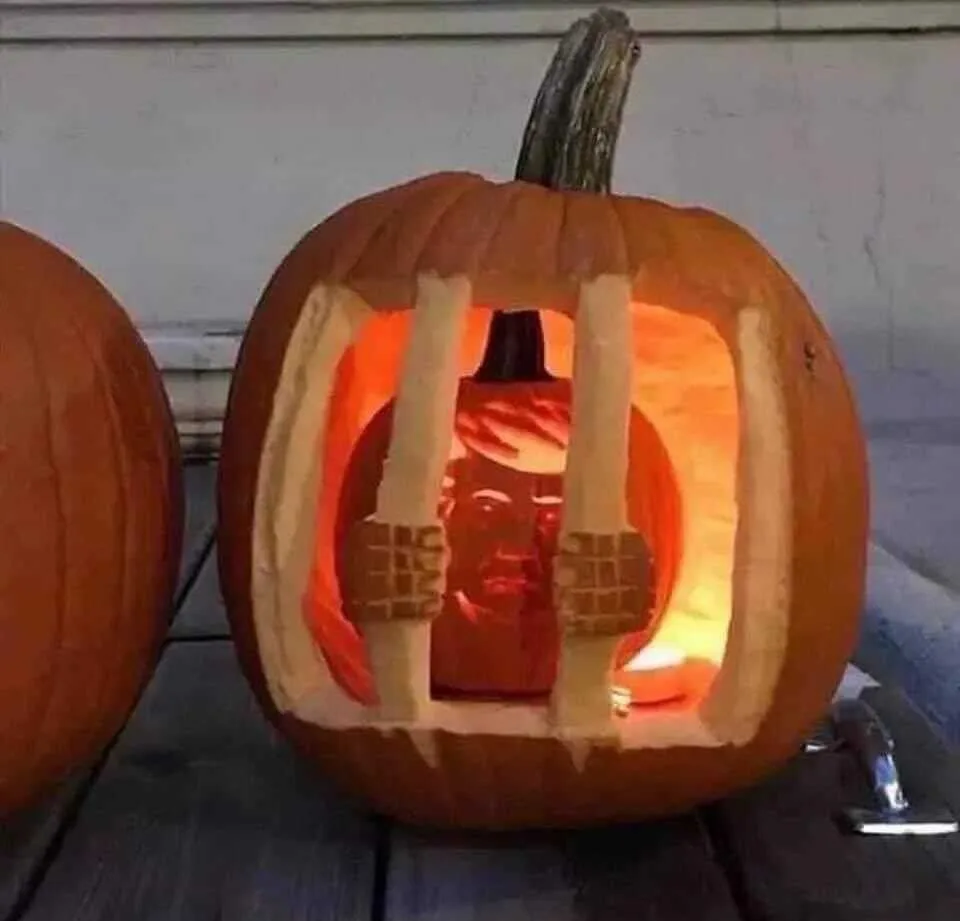 A carved pumpkin with a lit interior features a smaller pumpkin inside, intricately carved to resemble Donald Trump, behind…