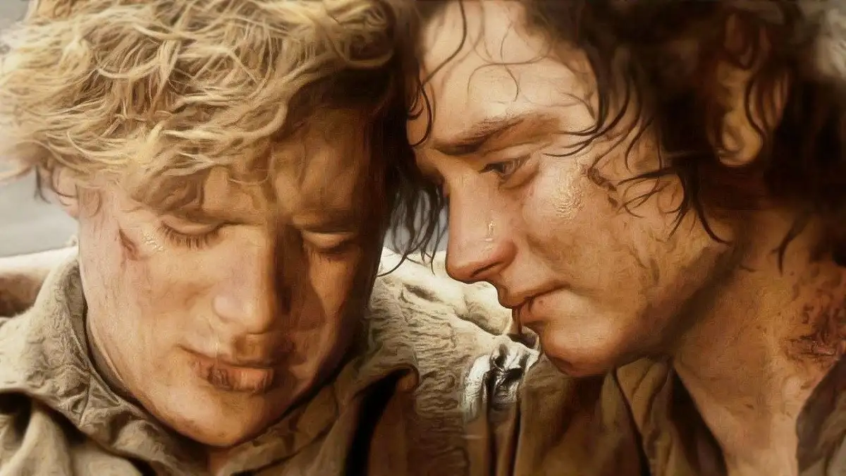 Two men with dirty, tear-streaked faces are shown in a close-up, one with blonde hair and the other with dark hair, both…