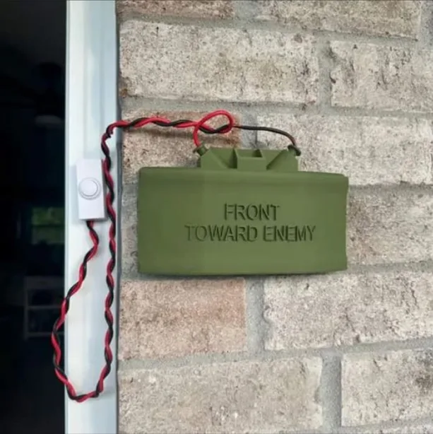 A green, rectangular object resembling a military grenade with the text 'FRONT TOWARD ENEMY' engraved on it is mounted on a…