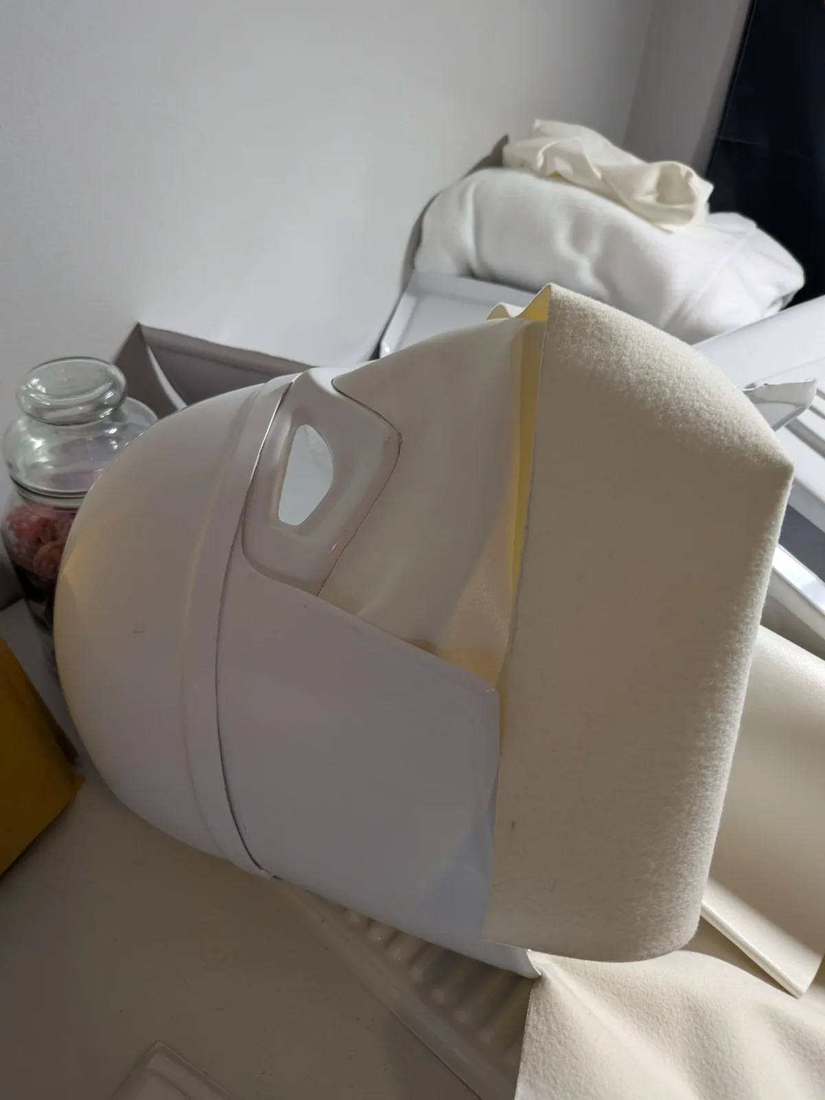 A white plastic milk jug is shown with a thick, off-white fabric or towel draped over its opening, creating a makeshift…