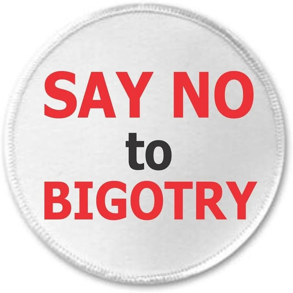 A circular white patch with a stitched border displays bold red text reading 'SAY NO' on top and 'BIGOTRY' at the bottom…