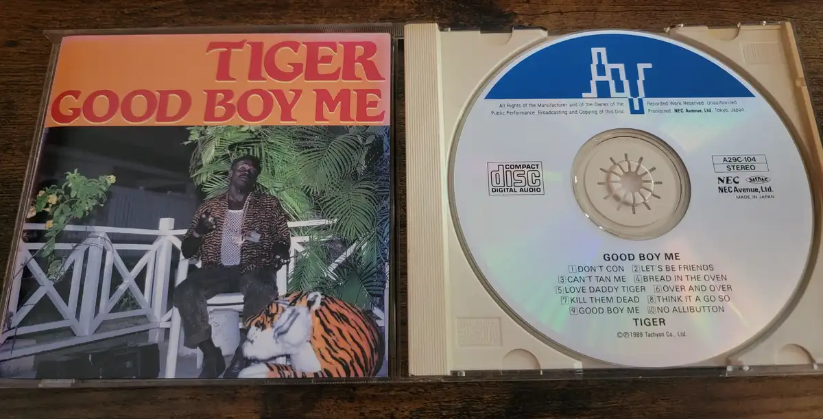 An open CD case displays the album 'GOOD BOY ME' by artist TIGER. The cover art shows a man in a tiger-print jacket sitting…