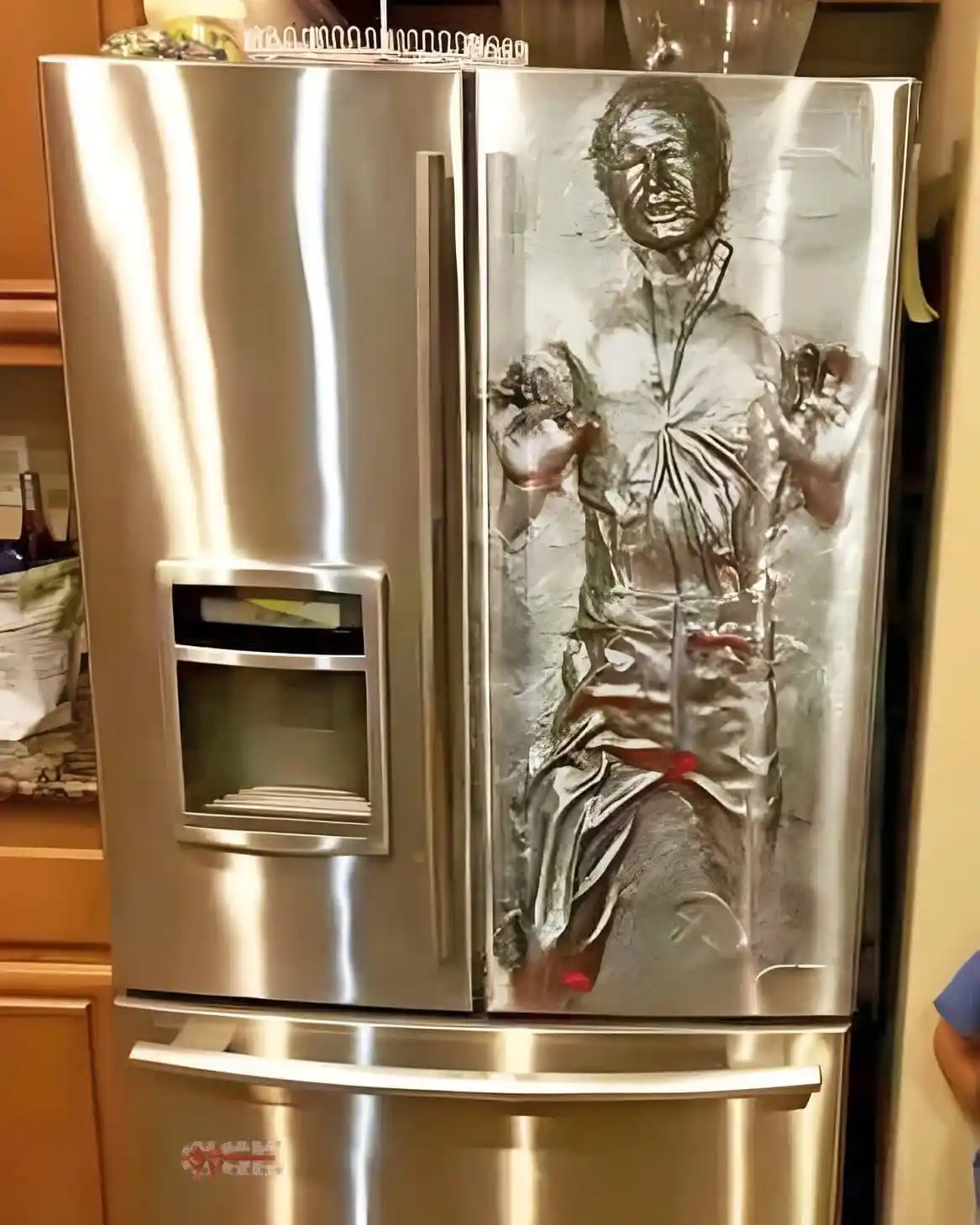 A stainless steel refrigerator has a large, frosty-looking image of a man frozen in a block of ice on its right door…