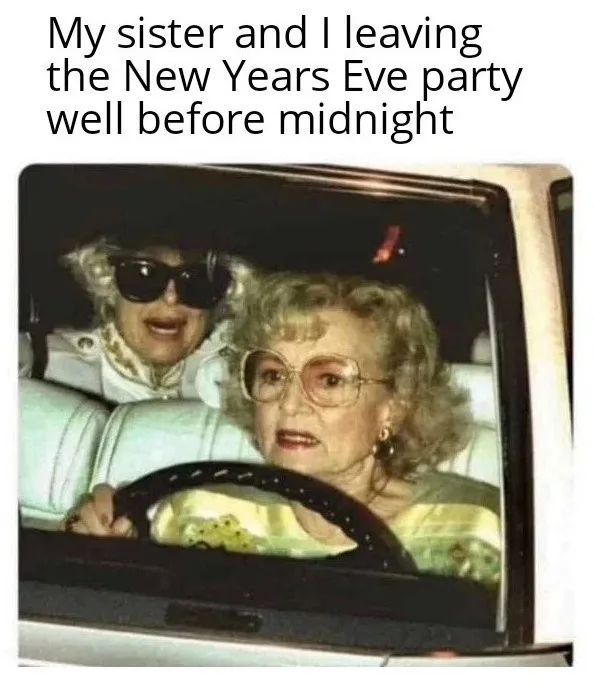 Two elderly women are in a car; the driver looks shocked or alarmed while the passenger in the back seat wears sunglasses…
