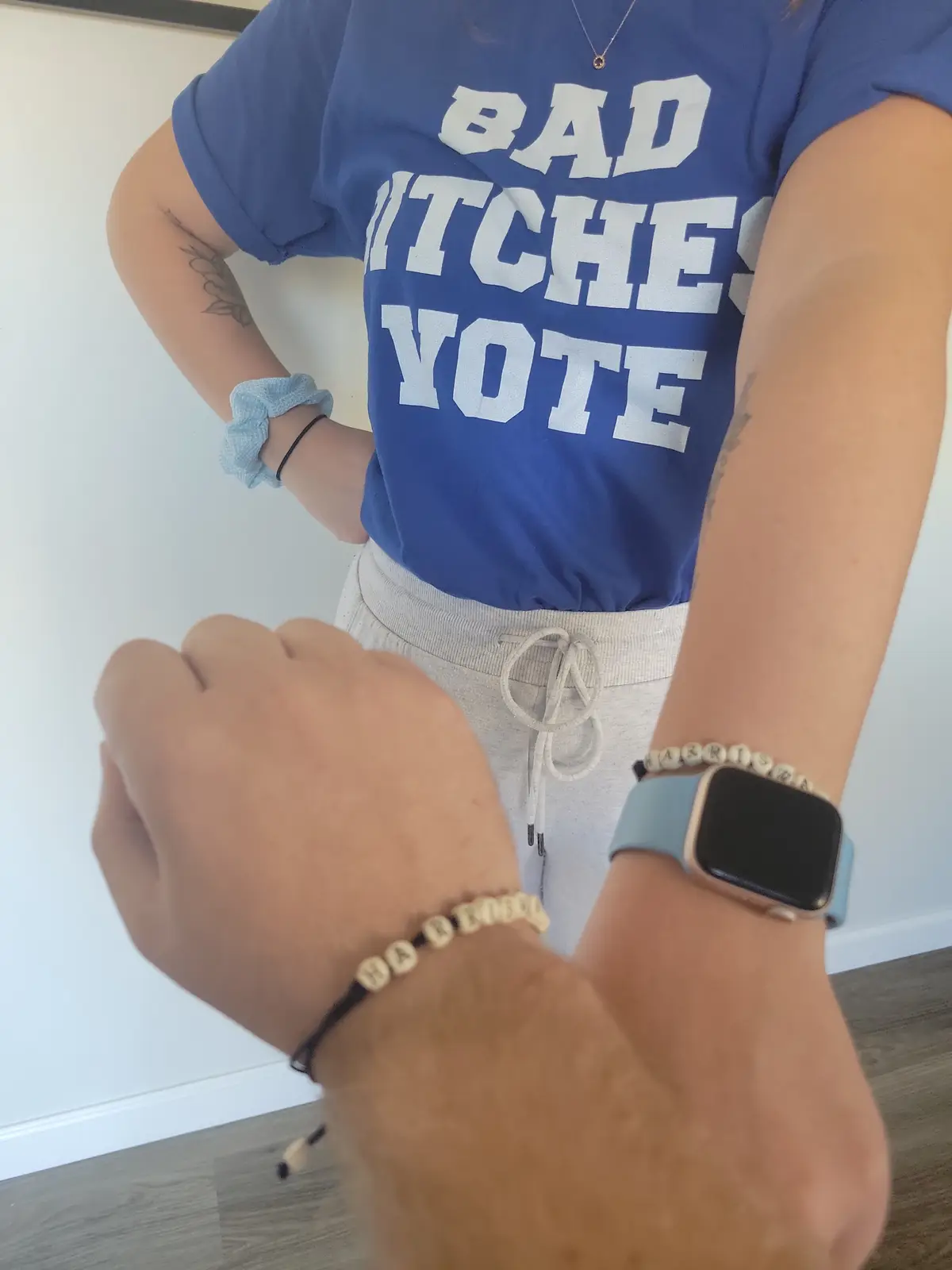 A person wearing a blue t-shirt with the text 'BAD WITCHES VOTE' in large white letters stands with hands on hips. In the…