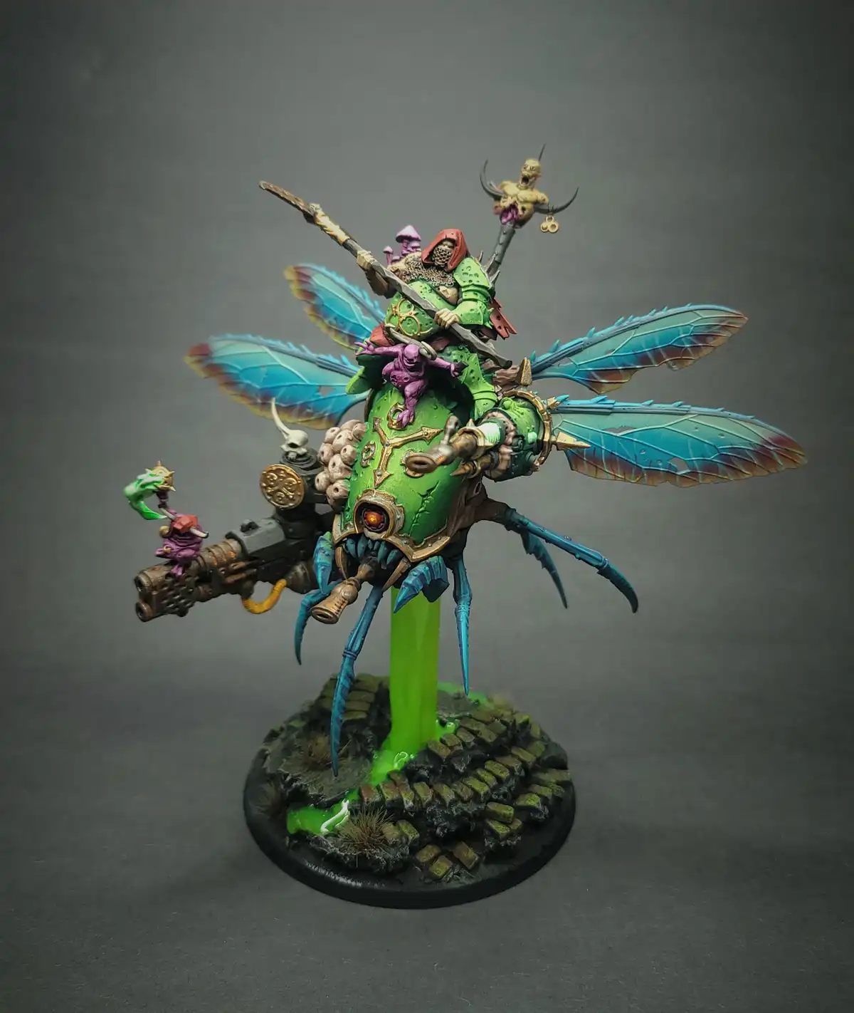 A highly detailed, painted miniature of a green-skinned, insectoid warlord mounted on a giant, multi-legged, fly-like…