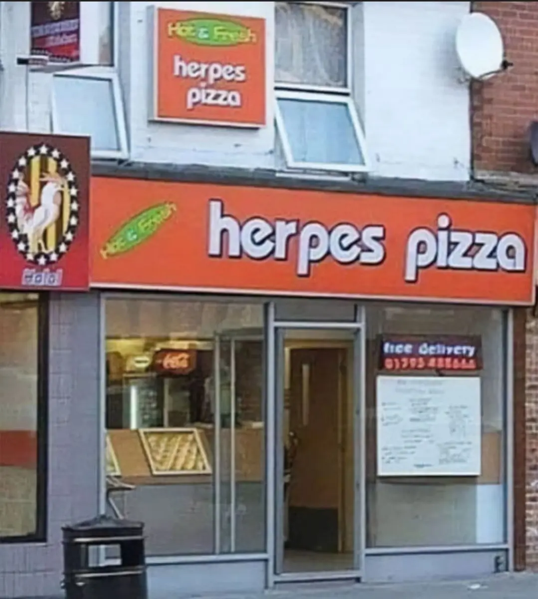 An exterior shot of a pizza restaurant with a large orange sign that reads 'herpes pizza' in bold white letters. Above the…