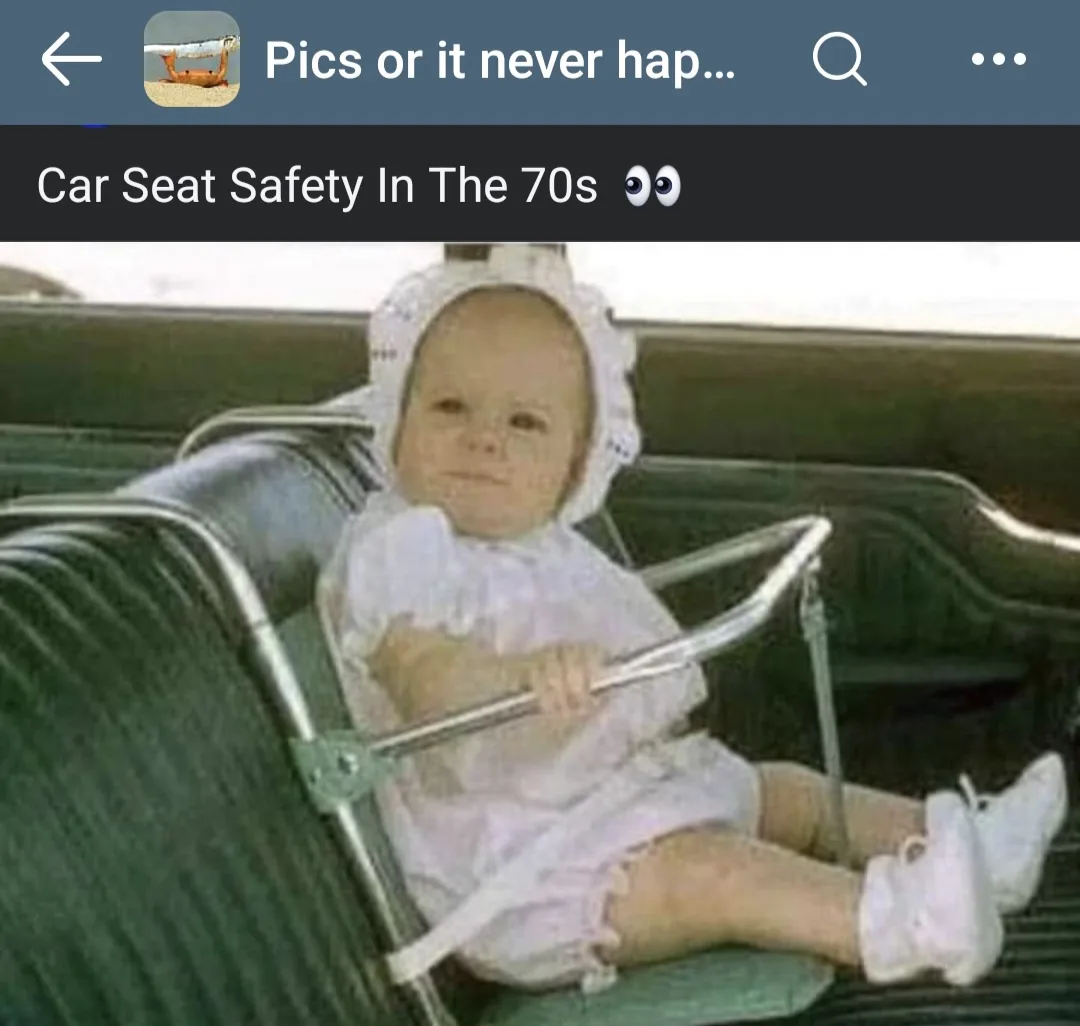 A vintage photo shows a baby in a white outfit and bonnet sitting in a car seat that appears to be a metal-framed, open-back…