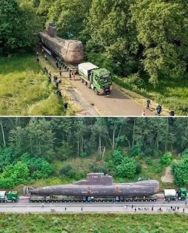 Two aerial photos show a large, rusty submarine being transported on a multi-axle flatbed truck along a narrow road through…