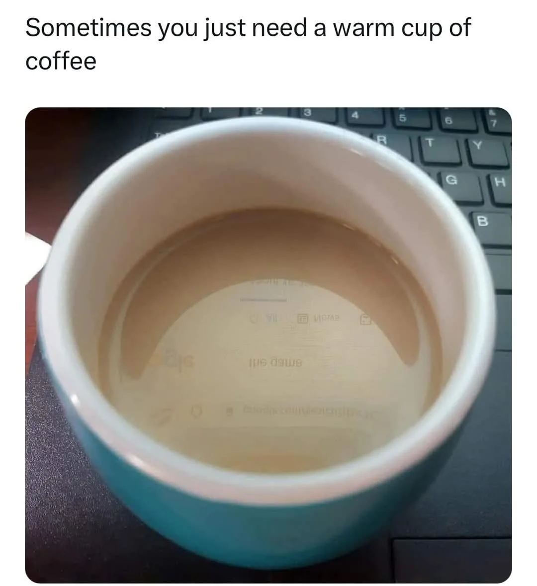 A top-down view of a teal ceramic mug with coffee, sitting on a black keyboard. The coffee is nearly empty, leaving a…
