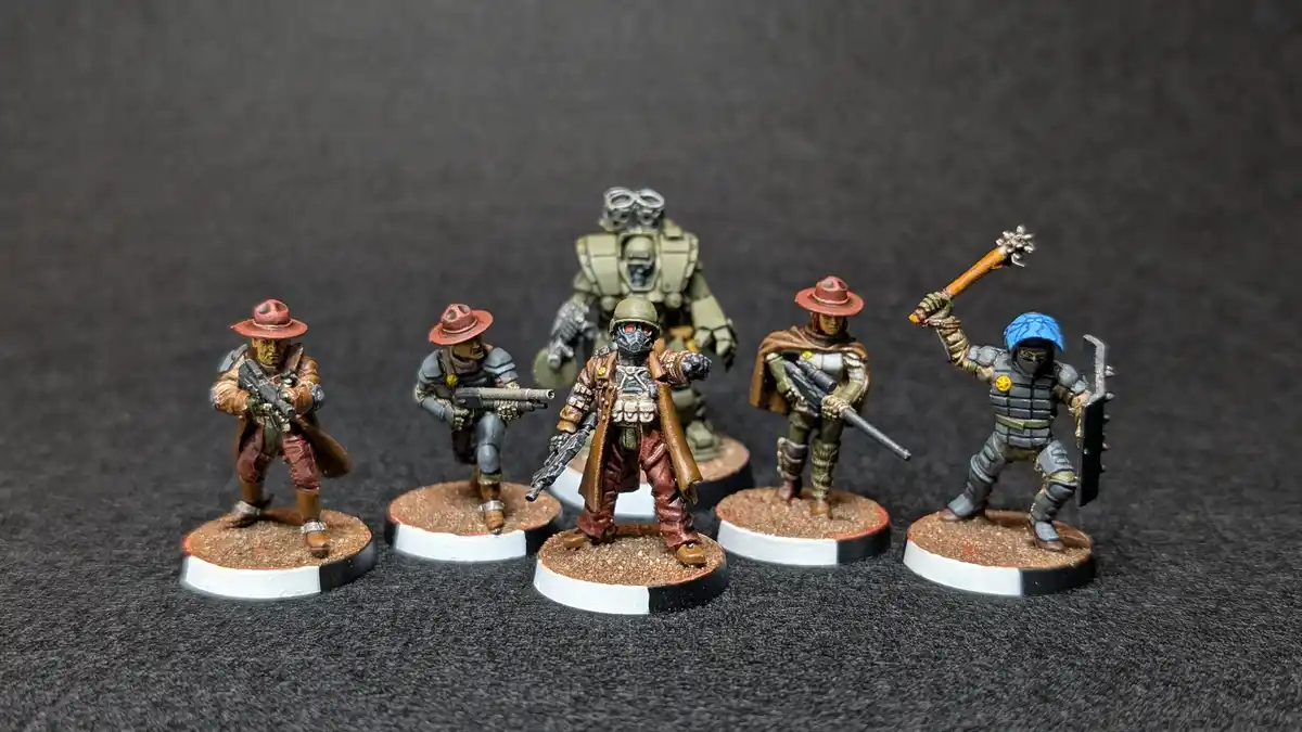 Six painted miniature figurines of armed characters, including a robot and a figure with a blue helmet, stand on circular…