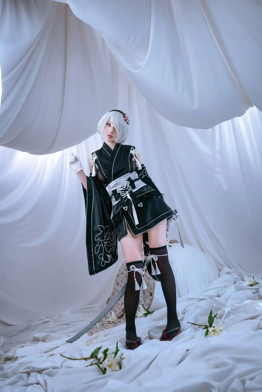A person in a detailed cosplay of the character Zero Two from the anime Darling in the Franxx, wearing a black and white…
