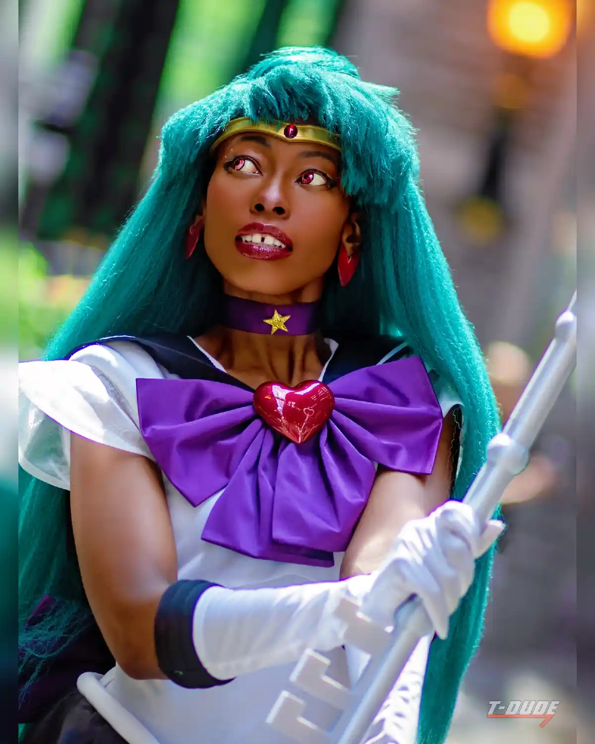 A person in a Sailor Uranus cosplay, featuring teal hair, a purple bow with a red heart, and a golden headband, holds a…