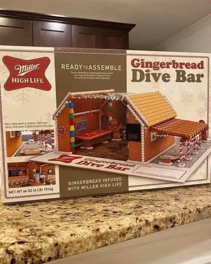 A product box for a 'Gingerbread Dive Bar' kit by Miller High Life sits on a kitchen counter. The box features an image of a…