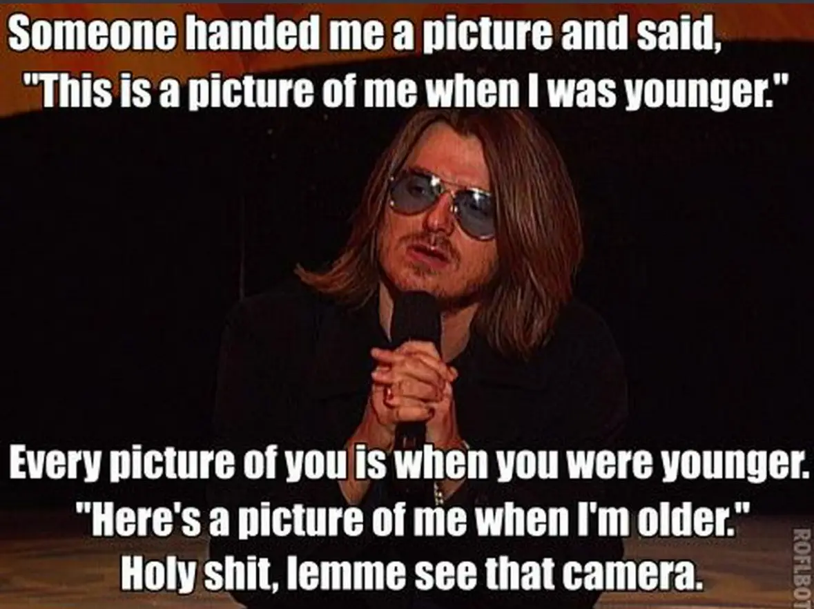 A man with long hair and sunglasses holds a microphone while looking surprised. White text overlaid on the image reads…
