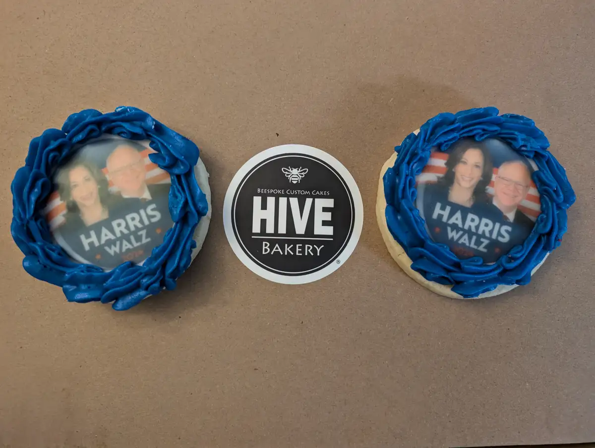 Two round cookies with blue frosting borders and printed campaign images of Kamala Harris and Tim Walz for the 2024…