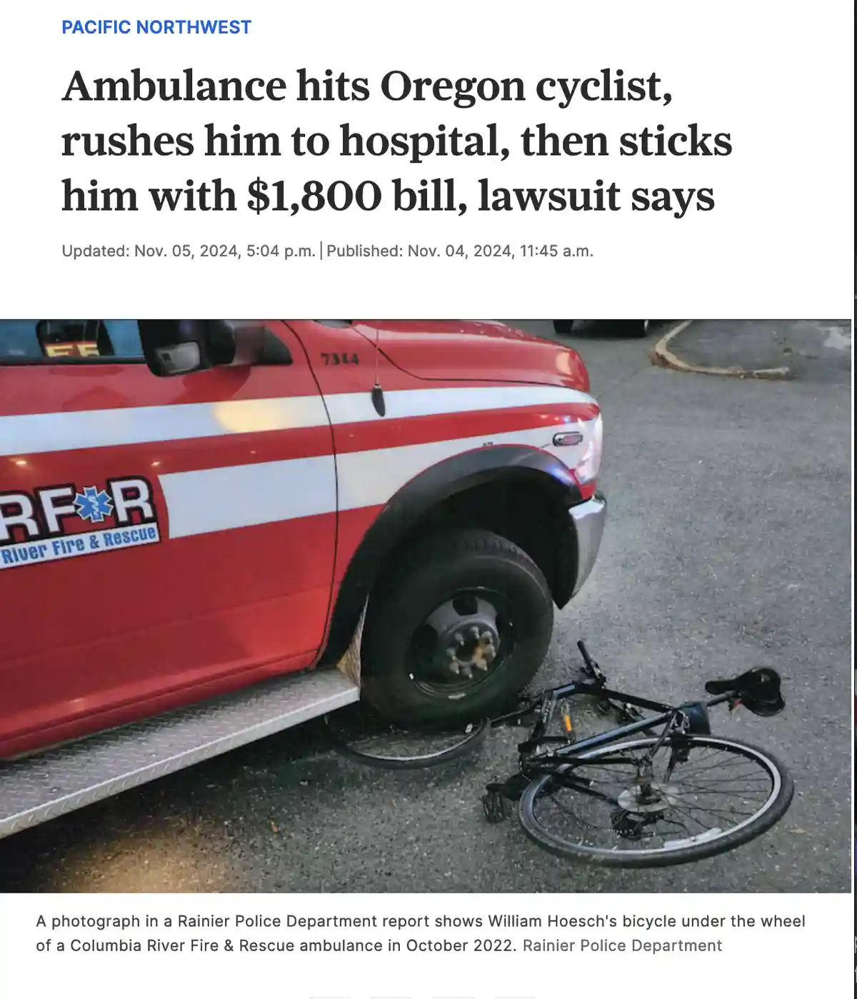 A red and white Columbia River Fire & Rescue ambulance is shown with a black bicycle crushed under its front wheel on an…