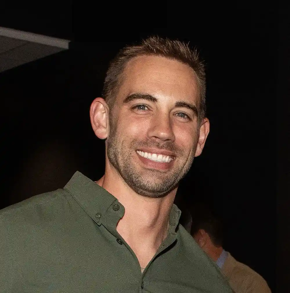 a smiling man with short brown hair and stubble wearing a green button-up shirt, overlaid with the text 'i'm not a fan of…