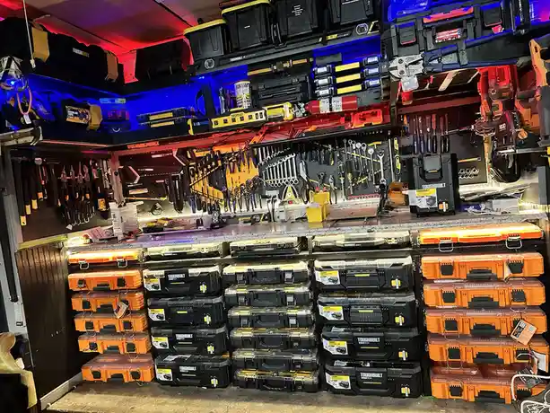 A highly organized, brightly lit garage workshop filled with stacks of orange and black ToughBuilt toolboxes, wall-mounted…