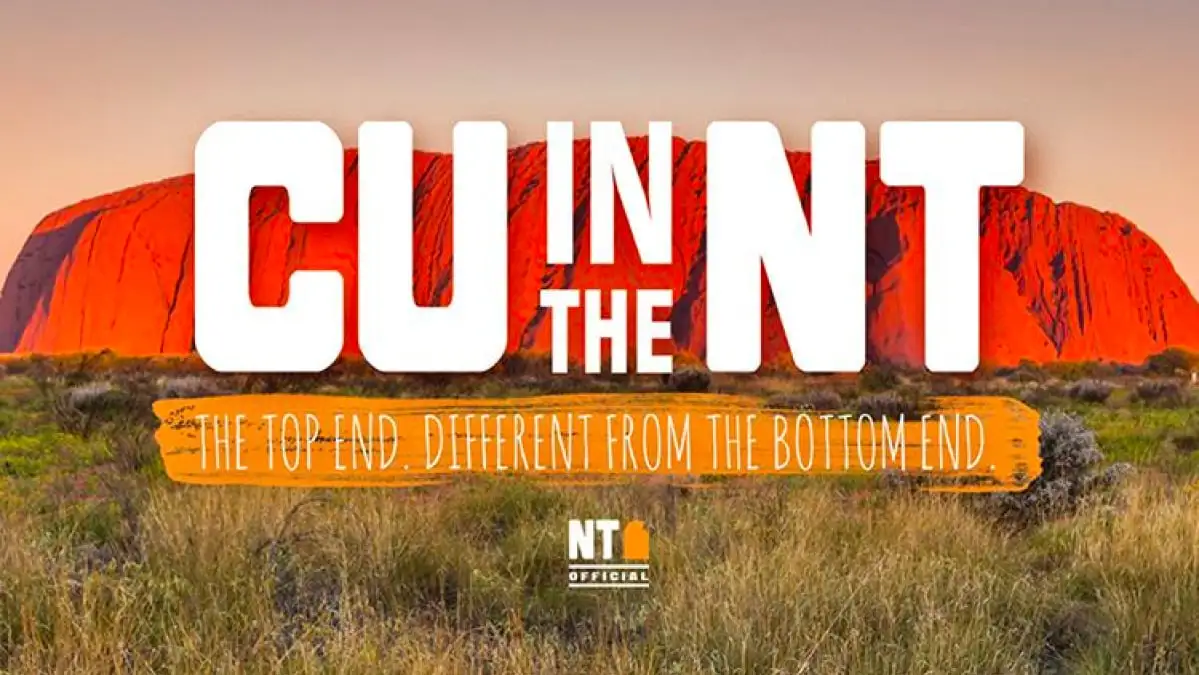 A landscape photo of Uluru (Ayers Rock) at sunset with large white text reading 'CU IN THE NT' and smaller orange text below…