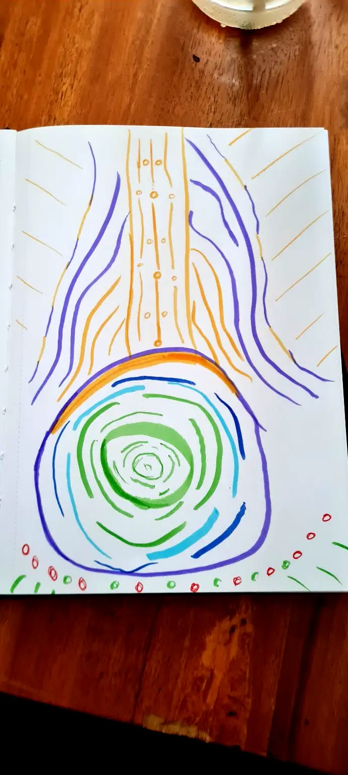A child's colorful drawing in a sketchbook depicts a swirling green vortex at the bottom, with orange and purple lines…