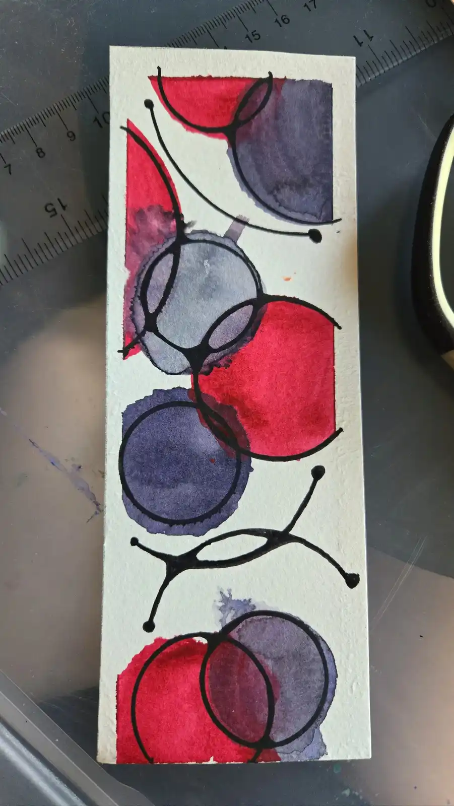 A watercolor and ink abstract artwork on white paper, featuring red and purple circular and semi-circular shapes outlined in…