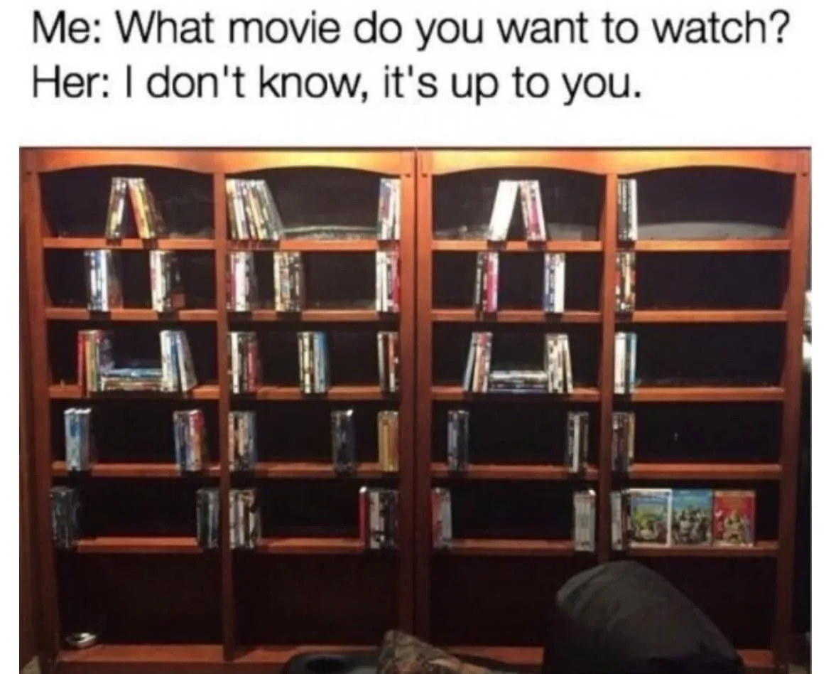 A photo of a large wooden bookshelf filled with DVDs, where several shelves have movies arranged to spell out the word 'A'…