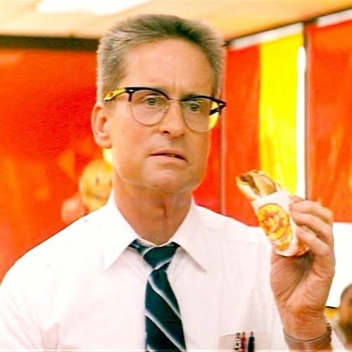 A man with glasses and a striped tie holds a wrapped sandwich, looking confused or disgusted. The overlaid text reads 'i'm…