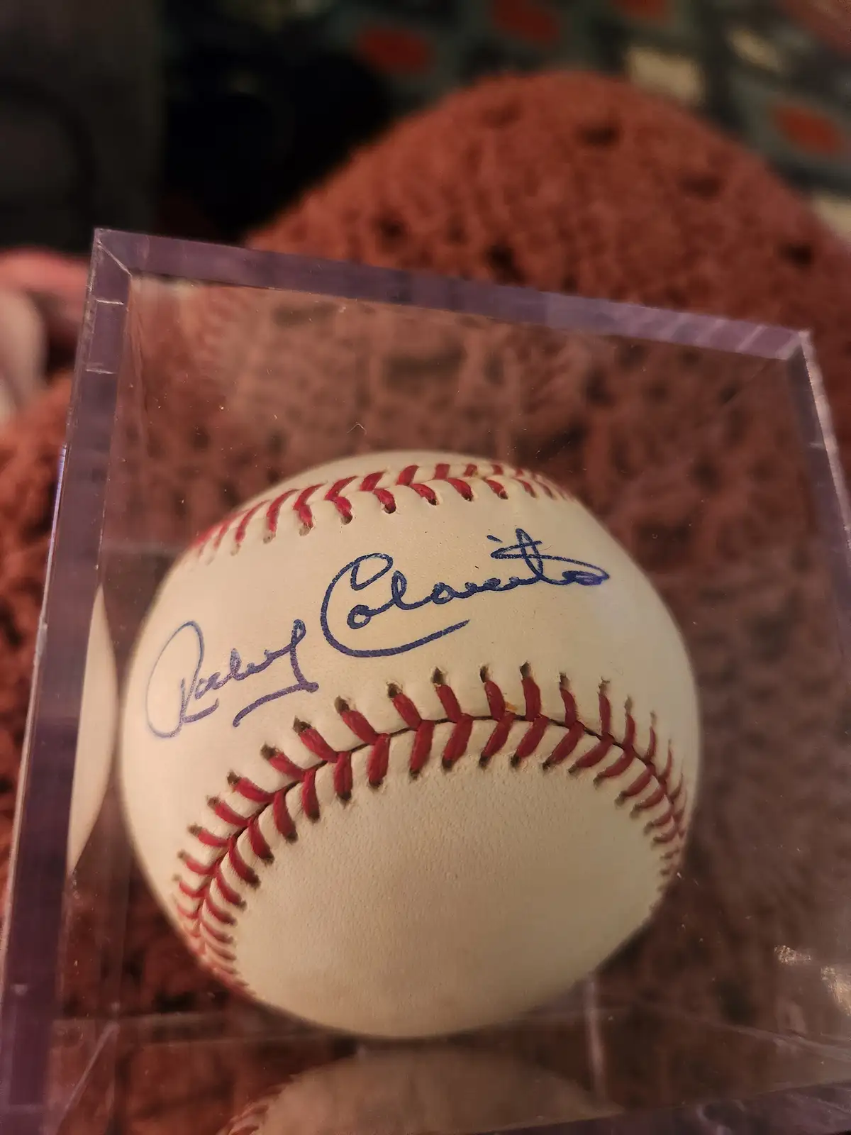 A close-up photo shows a white baseball with red stitching, signed in blue ink with the name 'Derek Jeter', displayed inside…