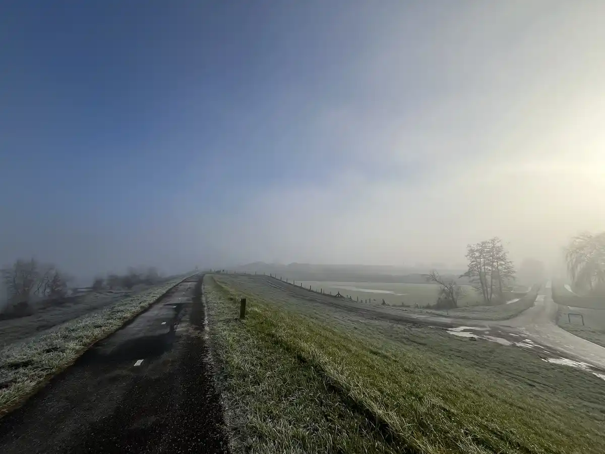 A frost-covered rural road splits into two paths under a hazy sky, with one path disappearing into fog. The overlaid text…