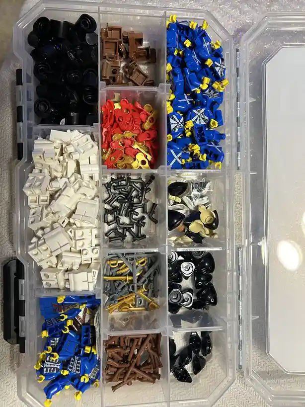 An overhead shot of a clear plastic organizer box filled with neatly sorted Lego pieces in multiple compartments, including…