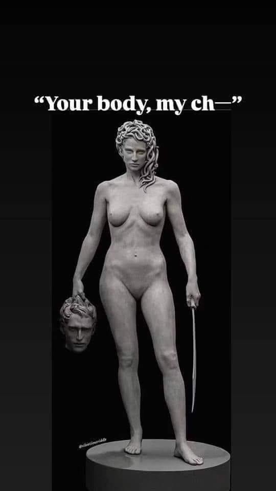 A grayscale statue of a female figure with Medusa-style snake hair, standing nude on a pedestal, holding a severed male head…