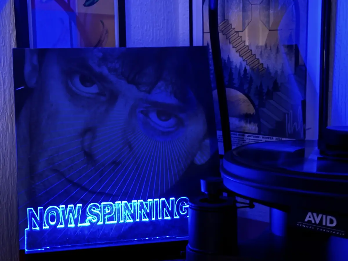 A close-up photo of a person's intense eyes with radiating lines, overlaid with glowing blue neon text reading 'NOW…