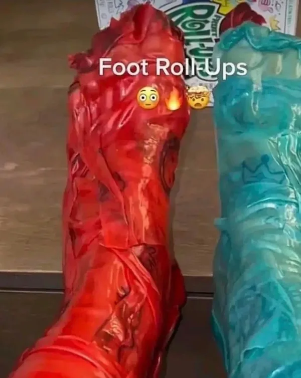 Two feet are wrapped in plastic bags, one red and one blue, with the text 'Foot Roll-Ups' overlaid. Two emojis, a surprised…