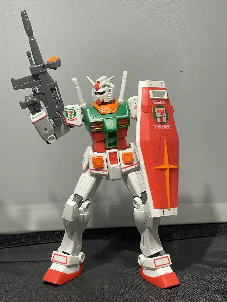 A custom-painted Gundam model, likely a RX-78-2, is shown standing with a rifle and shield. The entire figure is covered in…
